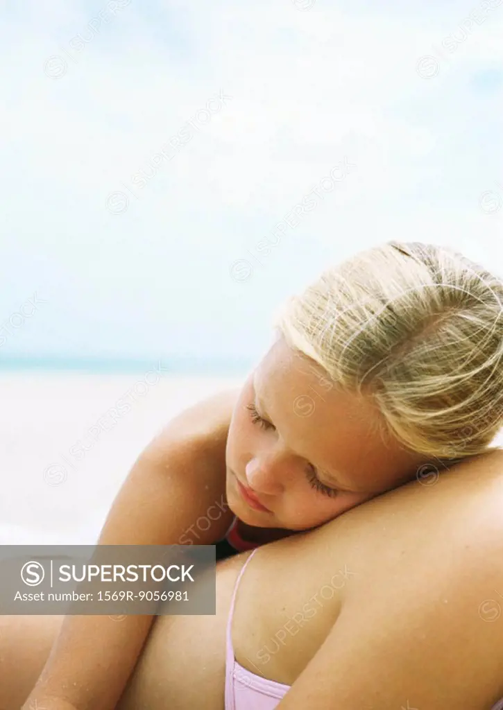 Little girl sleeping on mother´s back at the beach