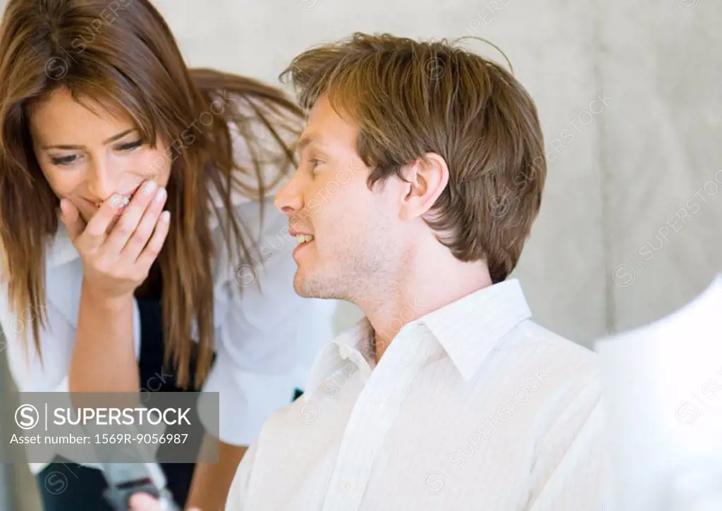 Man showing woman cell phone, woman laughing