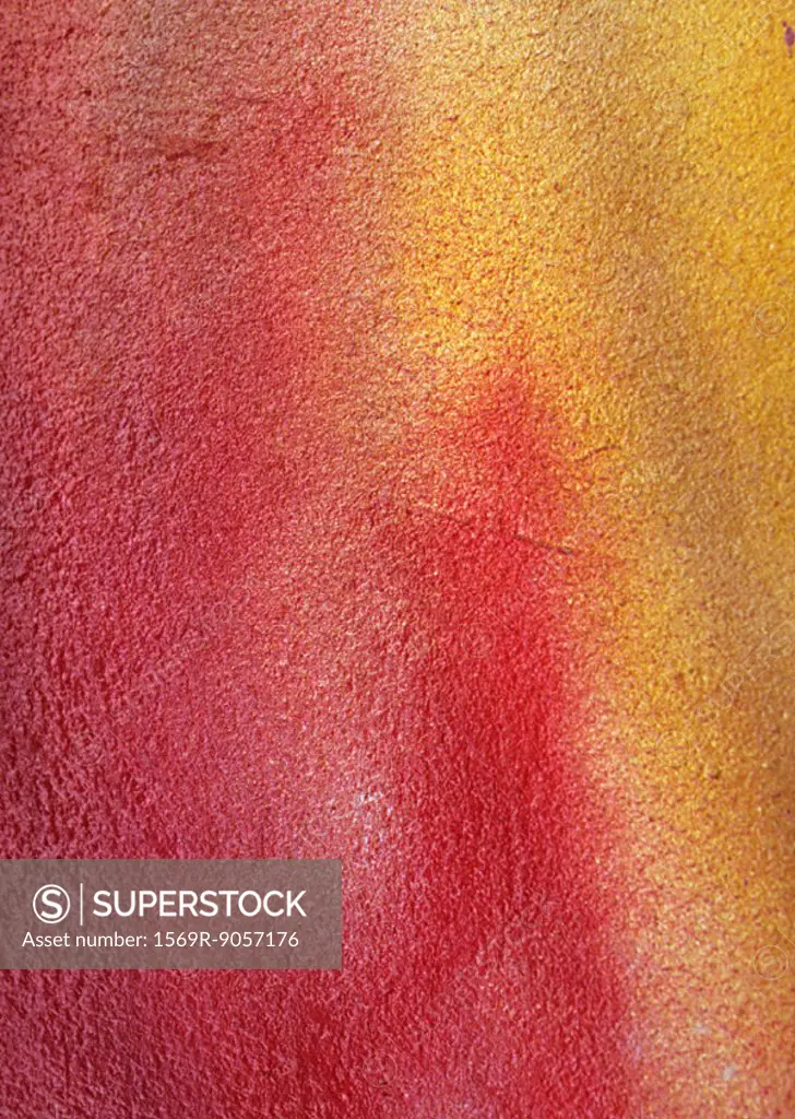 Red and yellow spray paint on concrete wall, close-up, full frame
