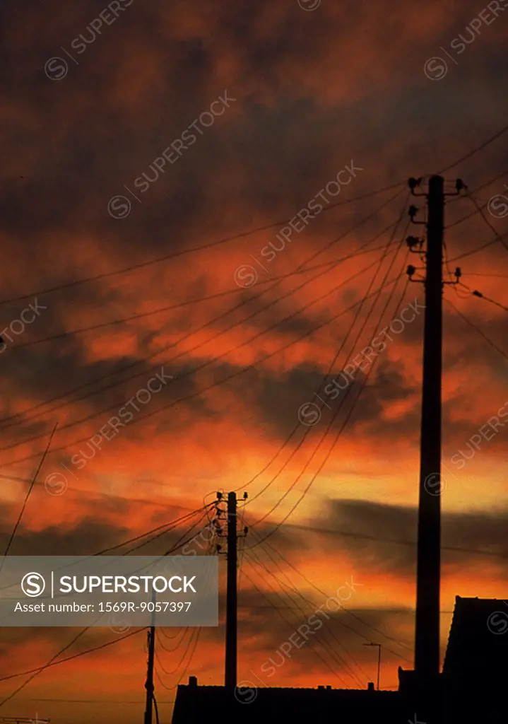 Electric poles silhouetted against red sky at sunset