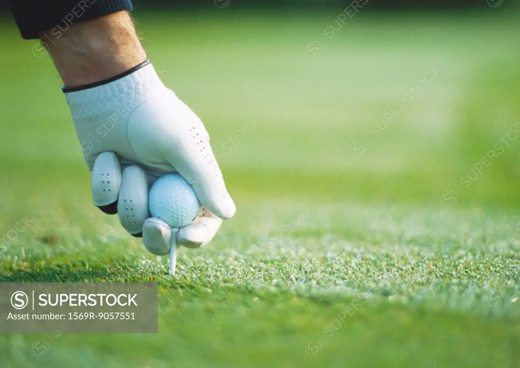 Golfer´s gloved hand teeing up, close-up