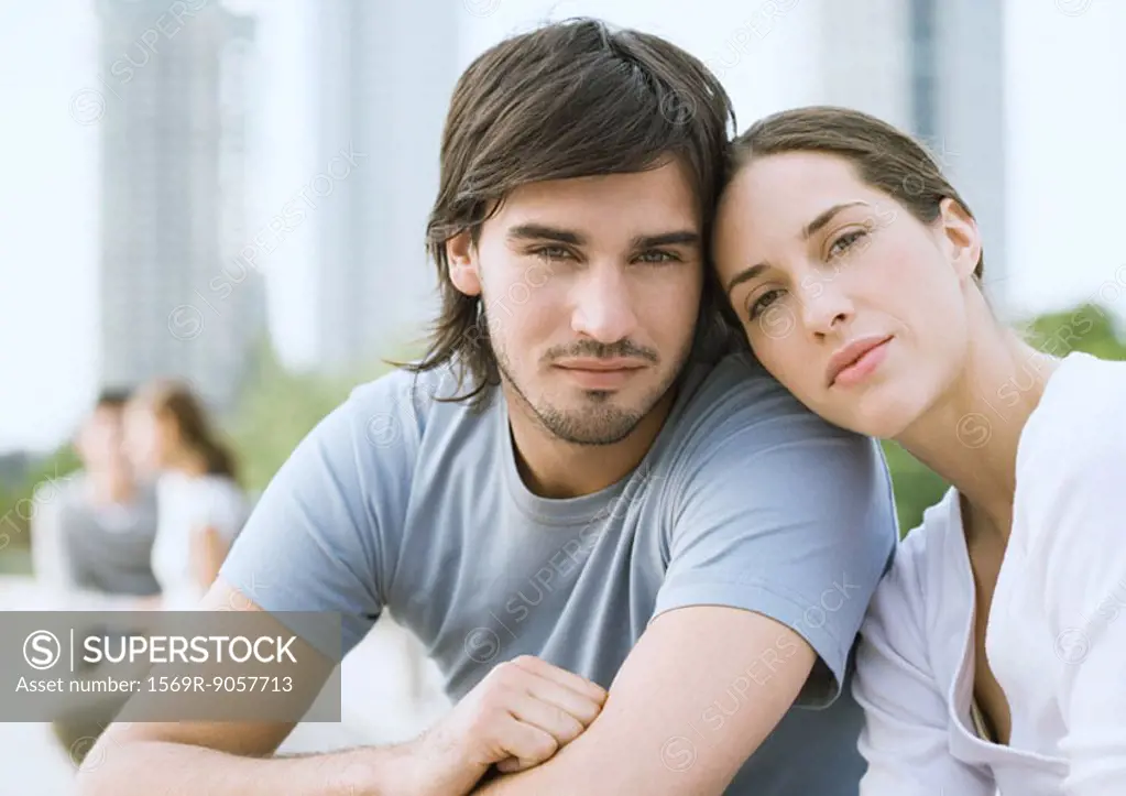 Young couple in urban park, woman resting head on man´s shoulder