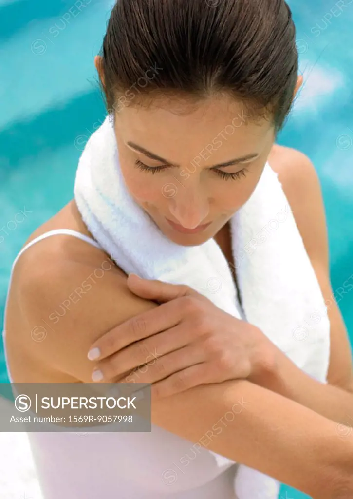 Woman with towel around neck looking at arm