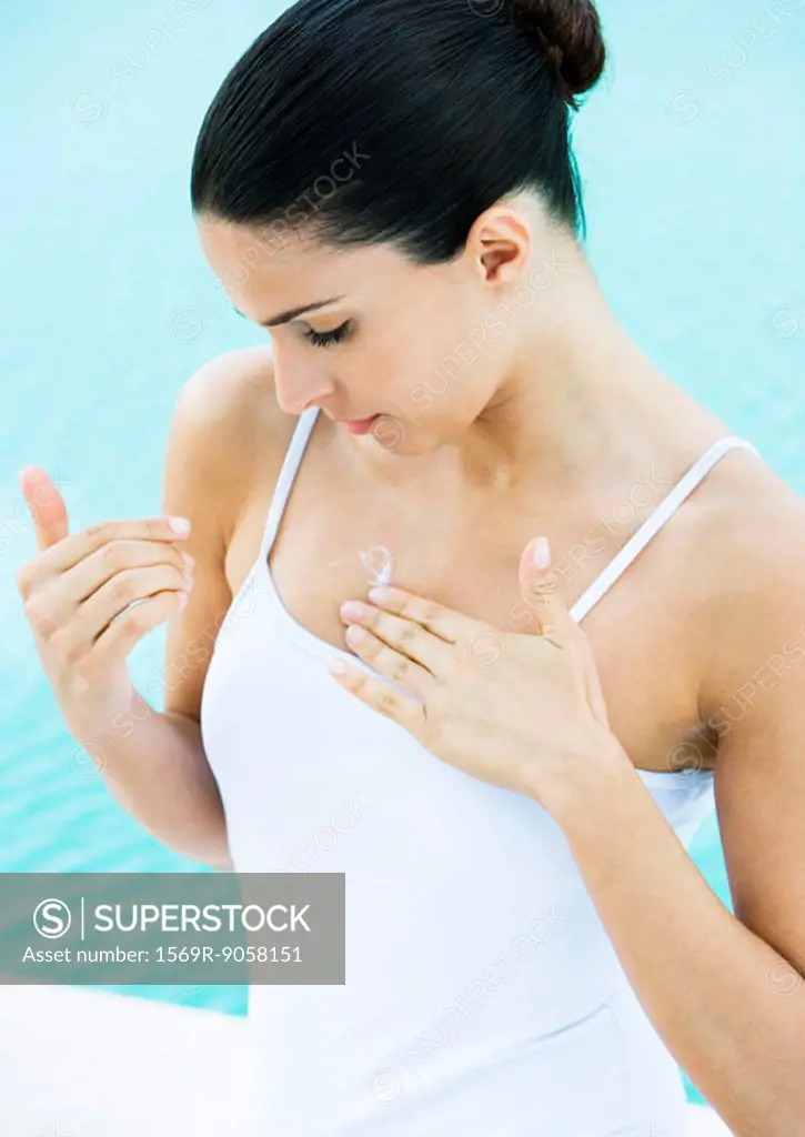 Woman applying sunscreen to chest