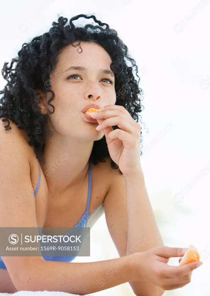 Young woman eating orange