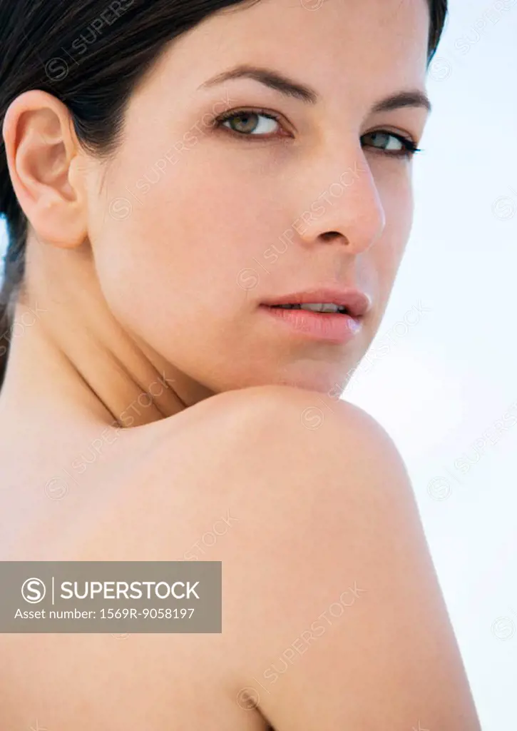 Woman looking over bare shoulder