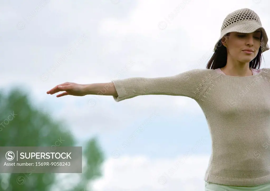 Woman standing outdoors with arms out, cropped