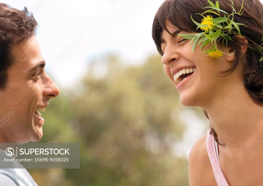 Young couple laughing, woman wearing flowers behind ear