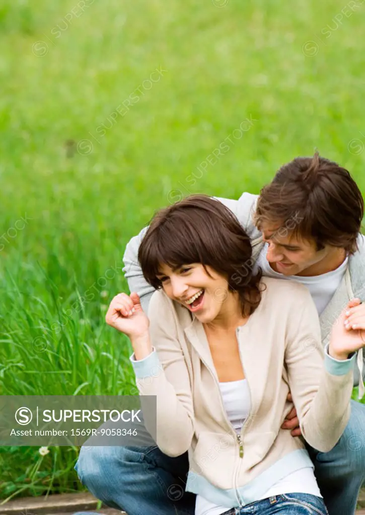 Young couple outdoors, man tickling woman