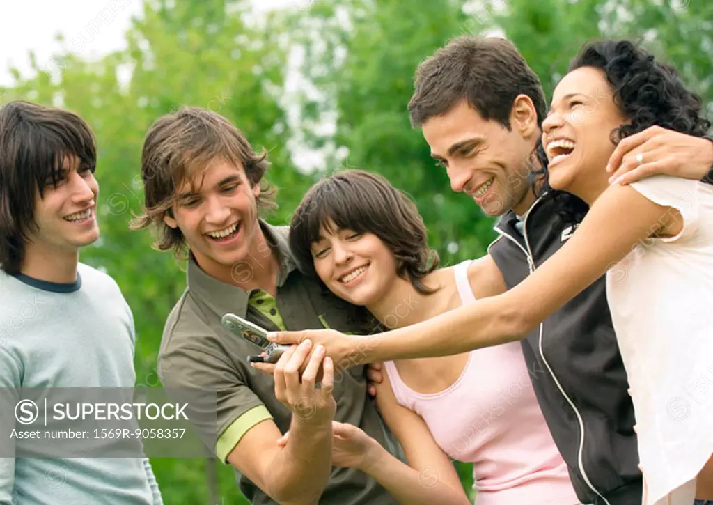 Group of young friends laughing and looking at cell phone