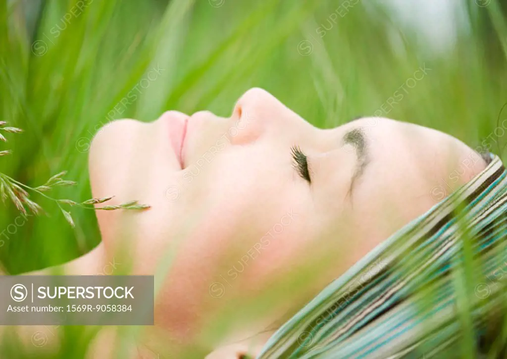 Young woman lying in grass, close-up of face
