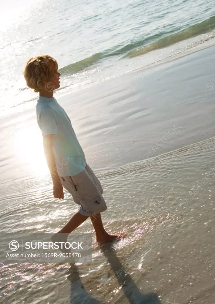 Boy walking in surf at beach