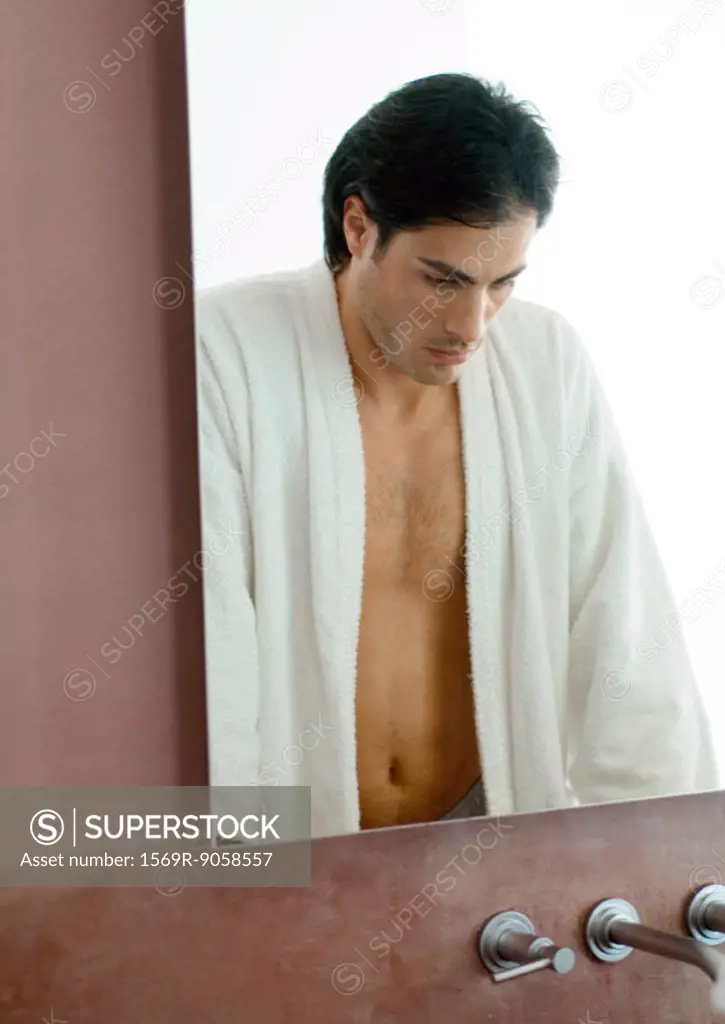 Man standing in bathroom, looking down