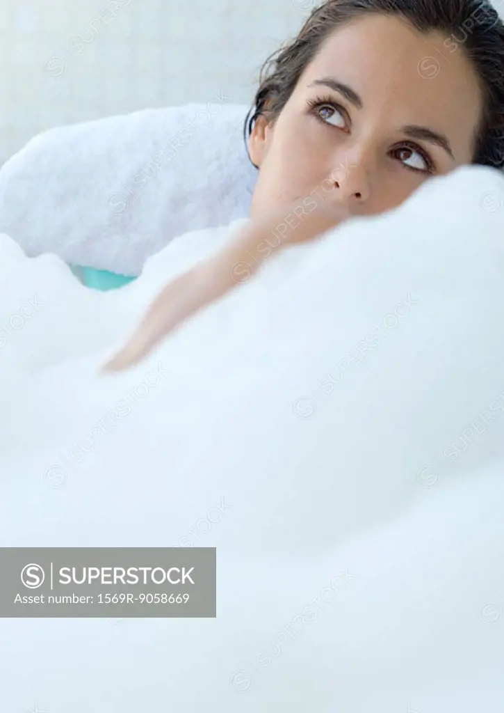 Woman taking bubble bath, looking up