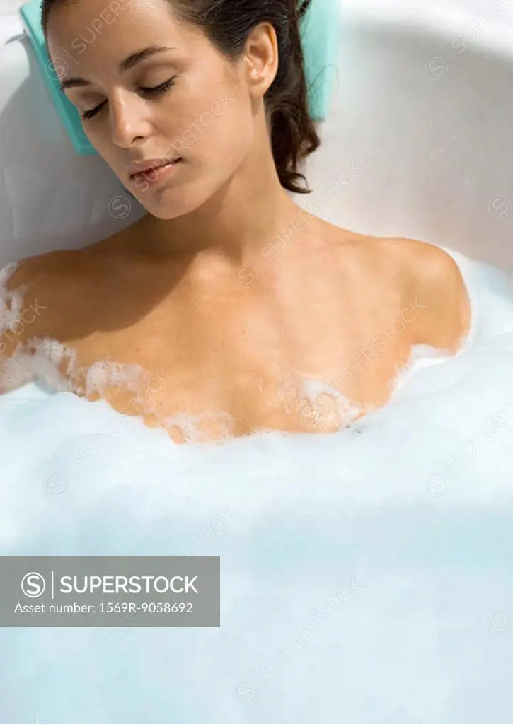 Woman reclining in bubble bath with eyes closed