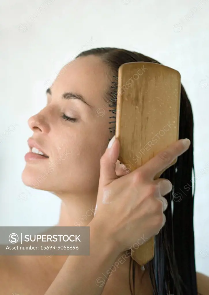 Woman brushing wet hair with eyes closed