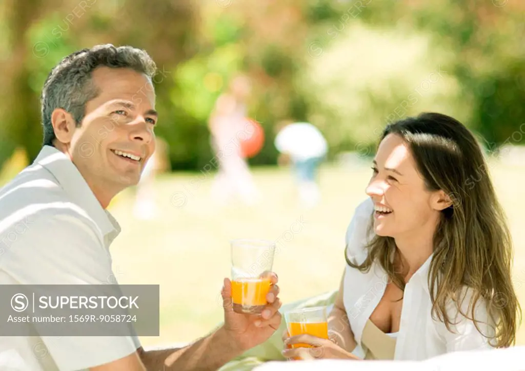 Couple holding glasses of juice outdoors