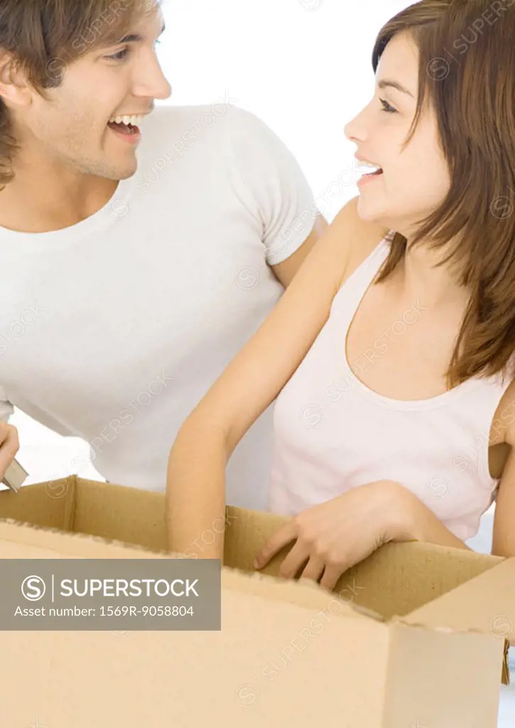 Couple unpacking cardboard box and smiling