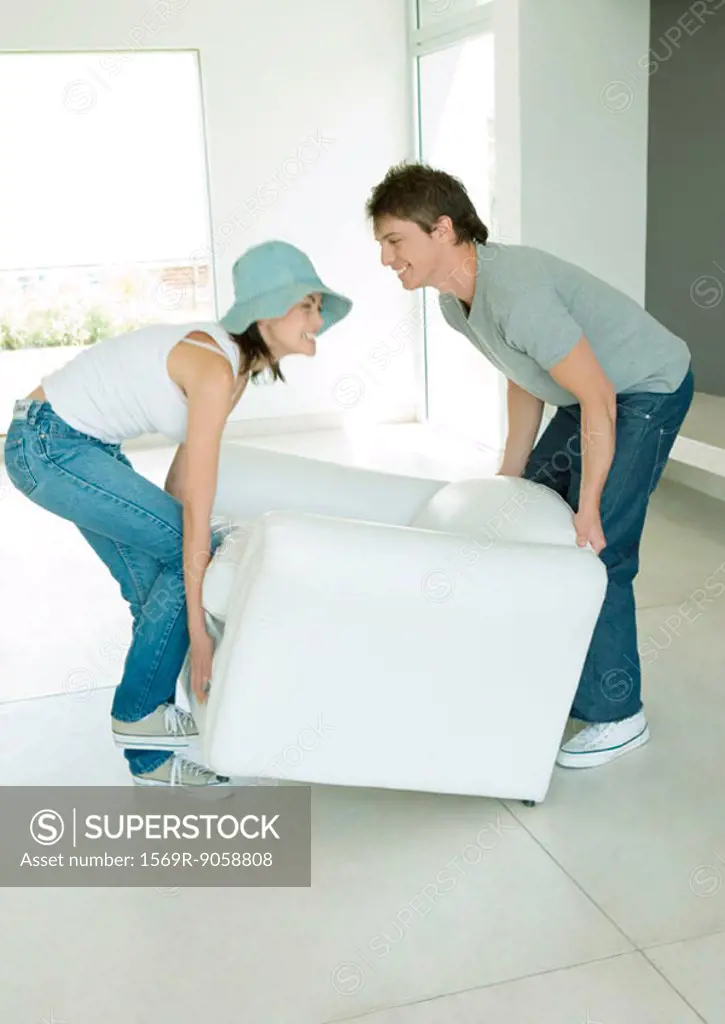 Couple moving armchair together