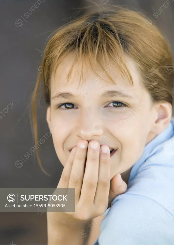 Girl covering mouth looking at camera, smiling, portrait, close-up