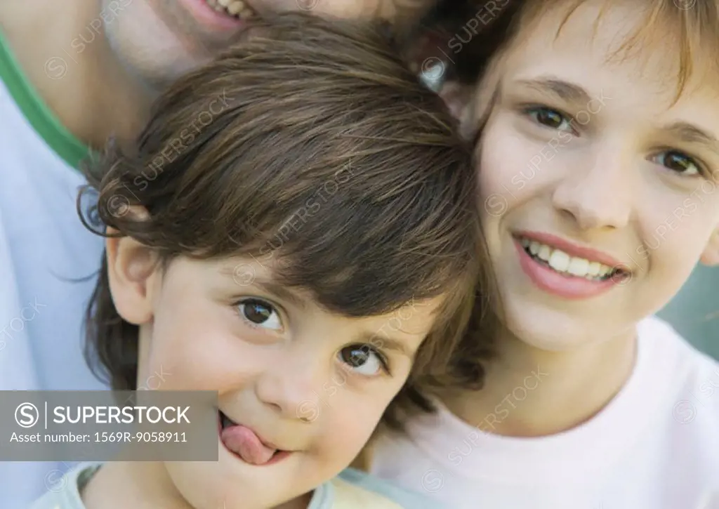 Father with two children, boy sticking out tongue, girl and father smiling, portrait, extreme close-up