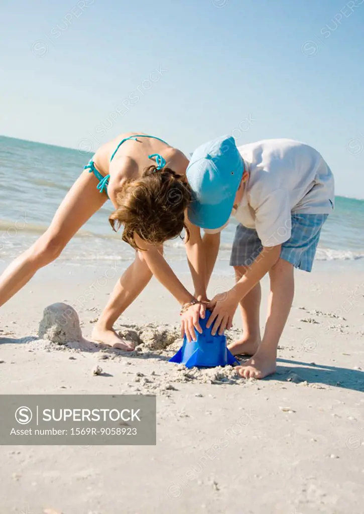 Boy and girl building sand castle together on beach