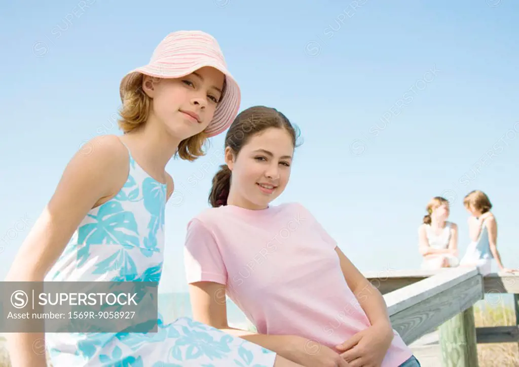 Preteen sisters leaning against wooden railing