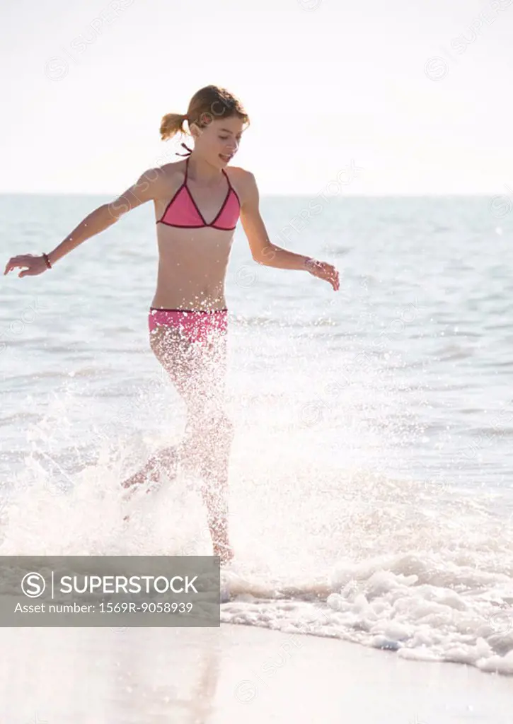 Girl running through surf on beach