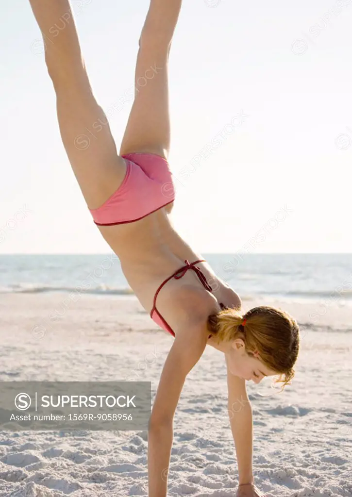 Girl doing handstand on beach