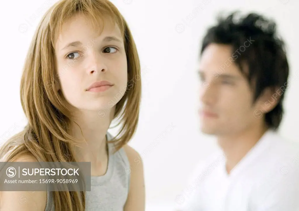 Preteen girl looking away, older brother in background