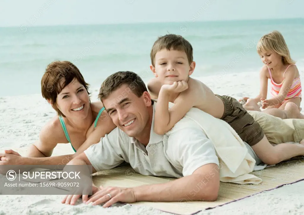 Family lying on beach, smiling