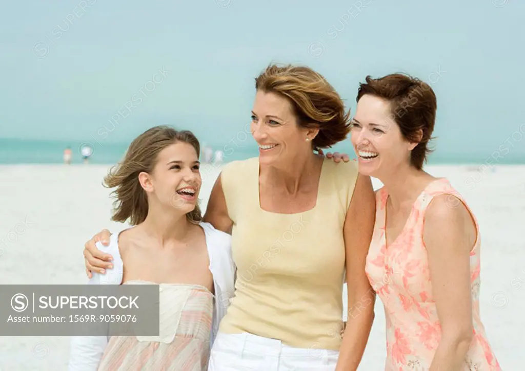 Three generations of women on beach, smiling