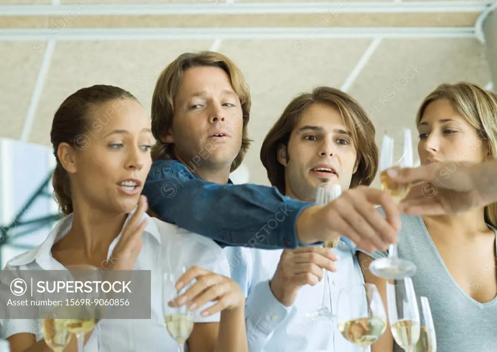 Man reaching over friends´ shoulders for glass of champagne