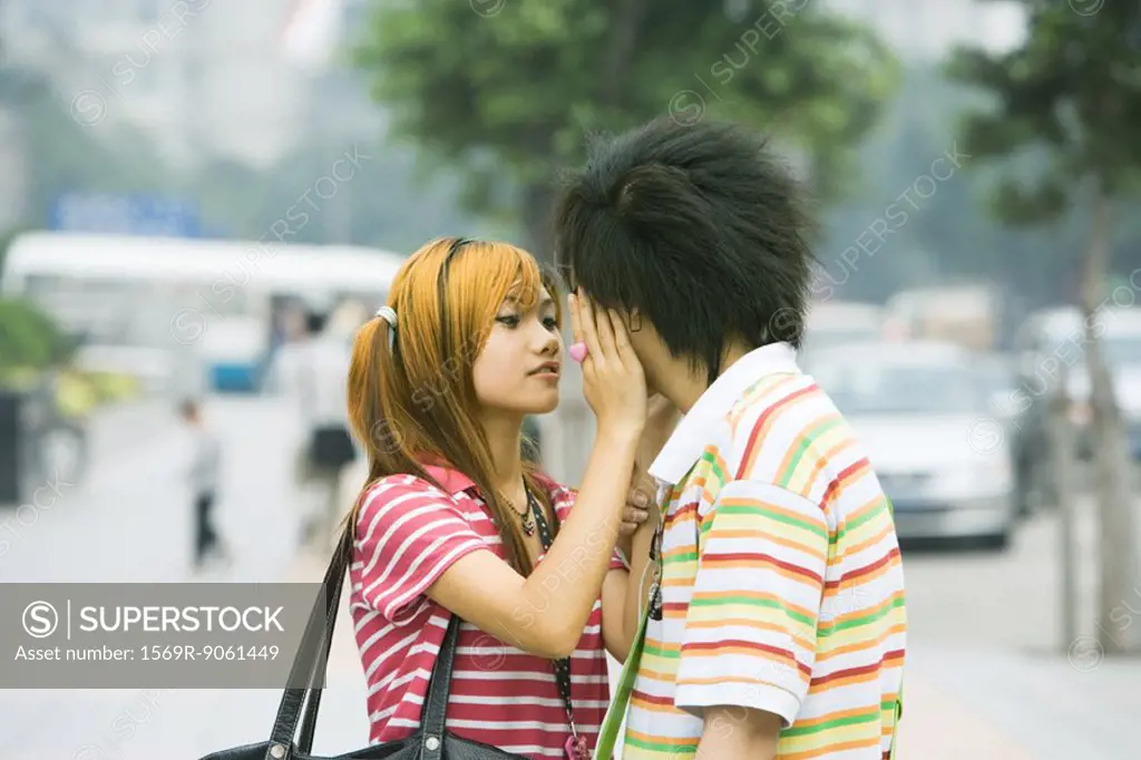 Teenage couple in urban setting, girl touching boy´s face
