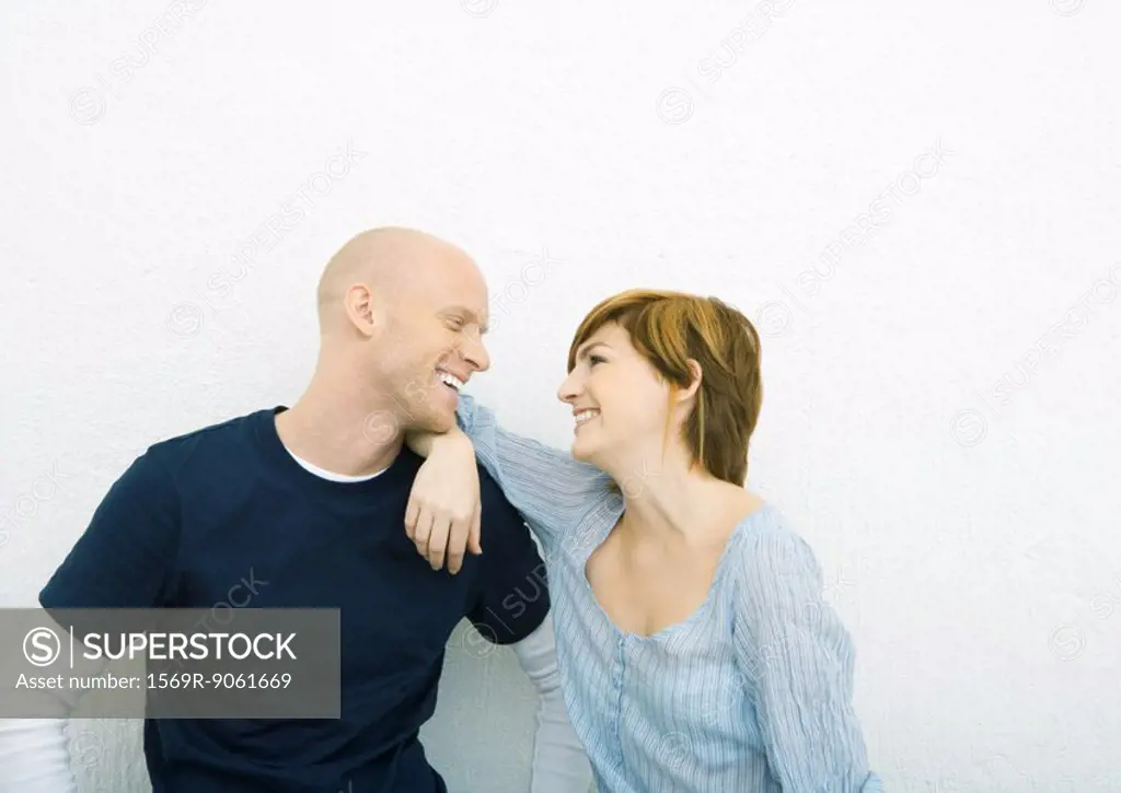 Young couple smiling at each other, face to face, woman with elbow on man´s shoulder