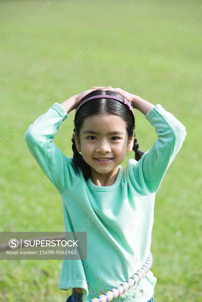 Girl playing with plastic hoop, smiling at camera
