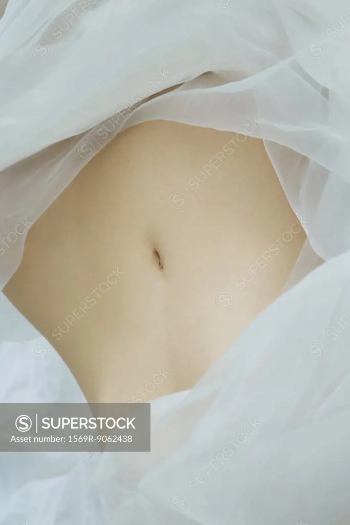 Woman´s abdomen, surrounded by sheer fabric, full frame