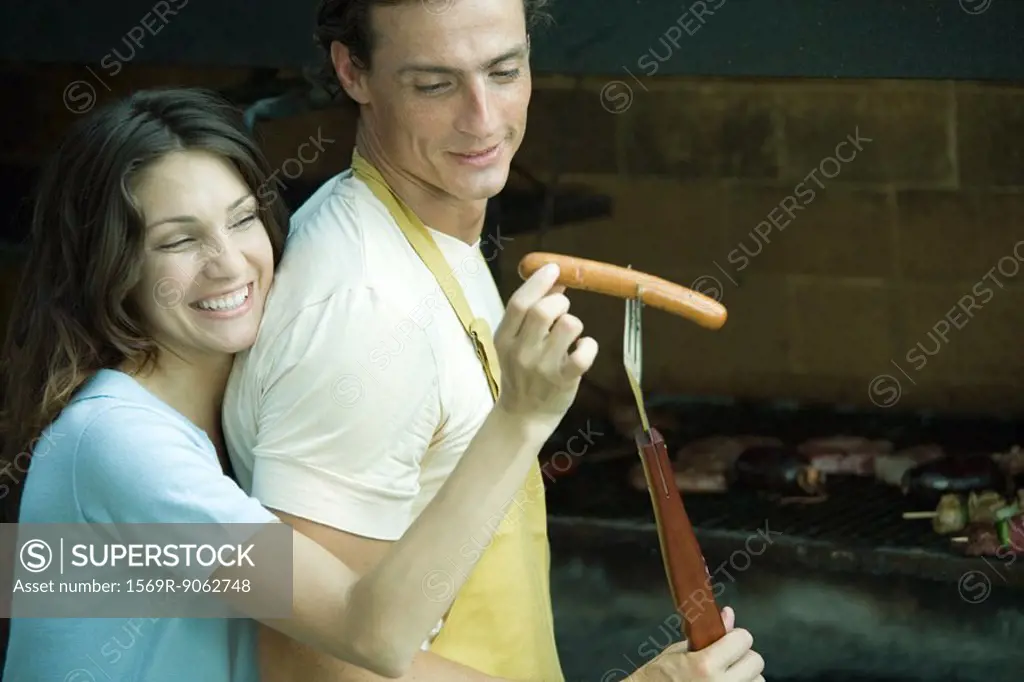 Couple having cookout, woman taking hotdog from man´s fork