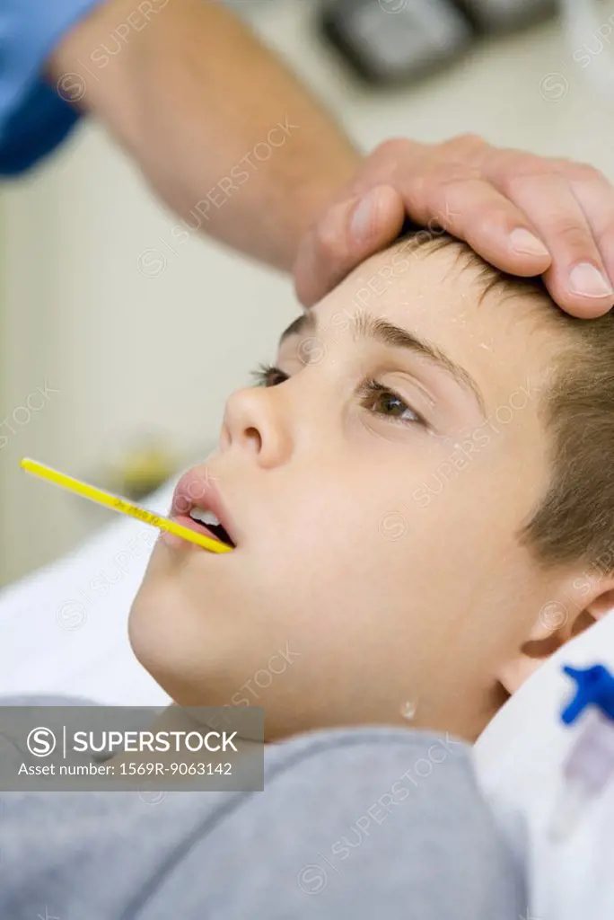 Boy with thermometer in mouth and man´s hand on forehead
