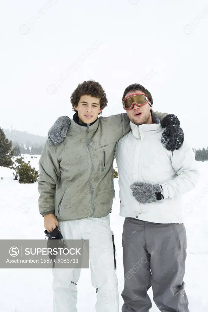 Two young skiers standing with arms around each other´s shoulders, smiling at camera, portrait