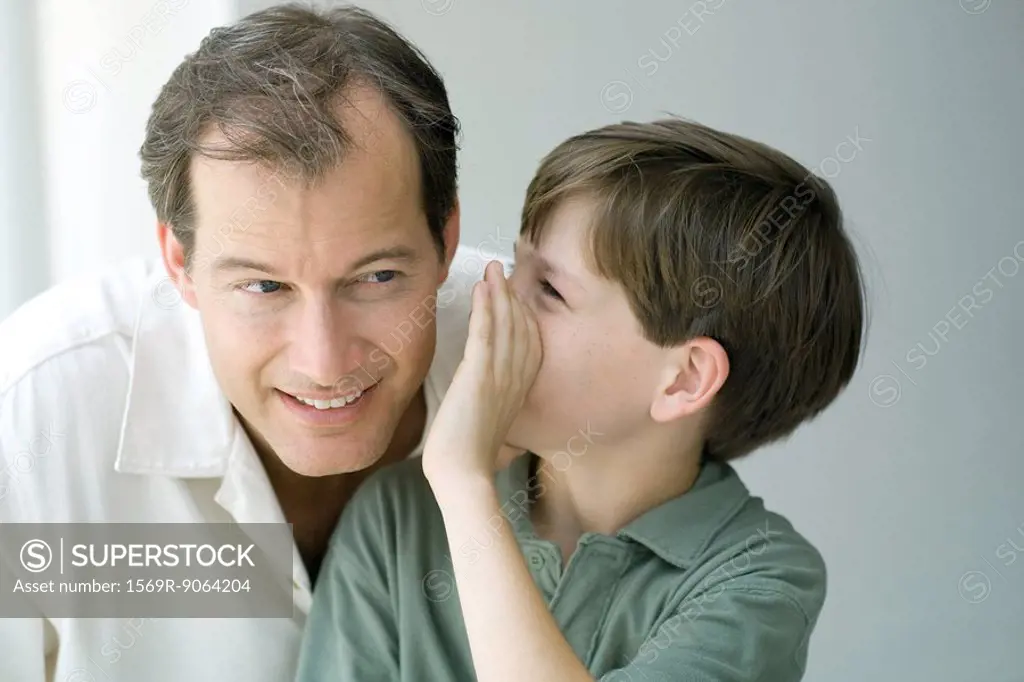 Boy whispering in father´s ear, close-up