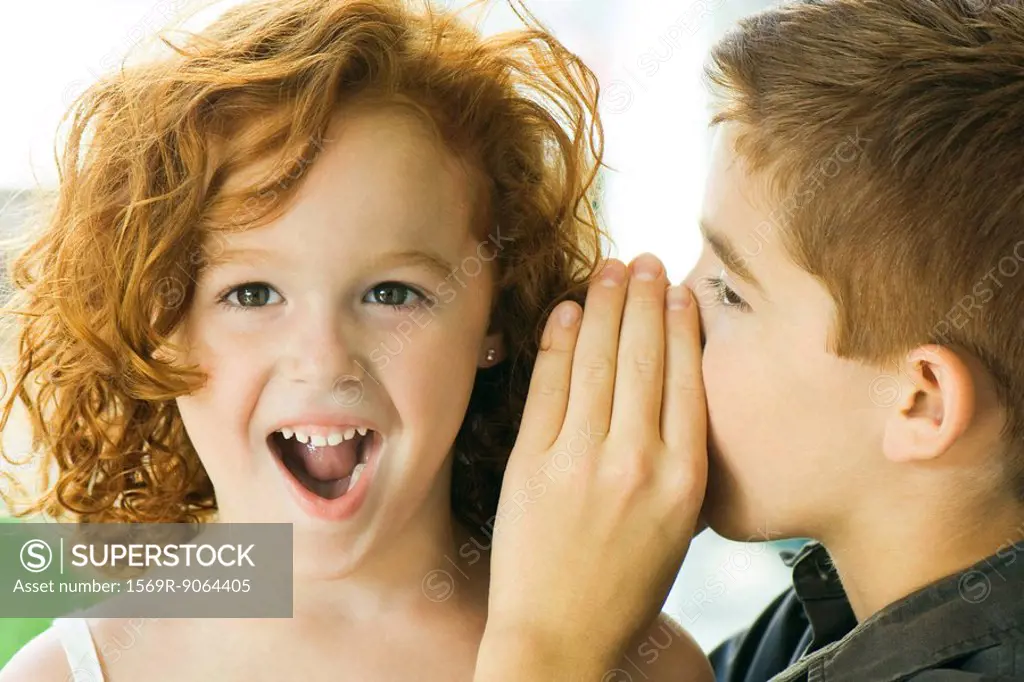Boy whispering in girl´s ear, close-up