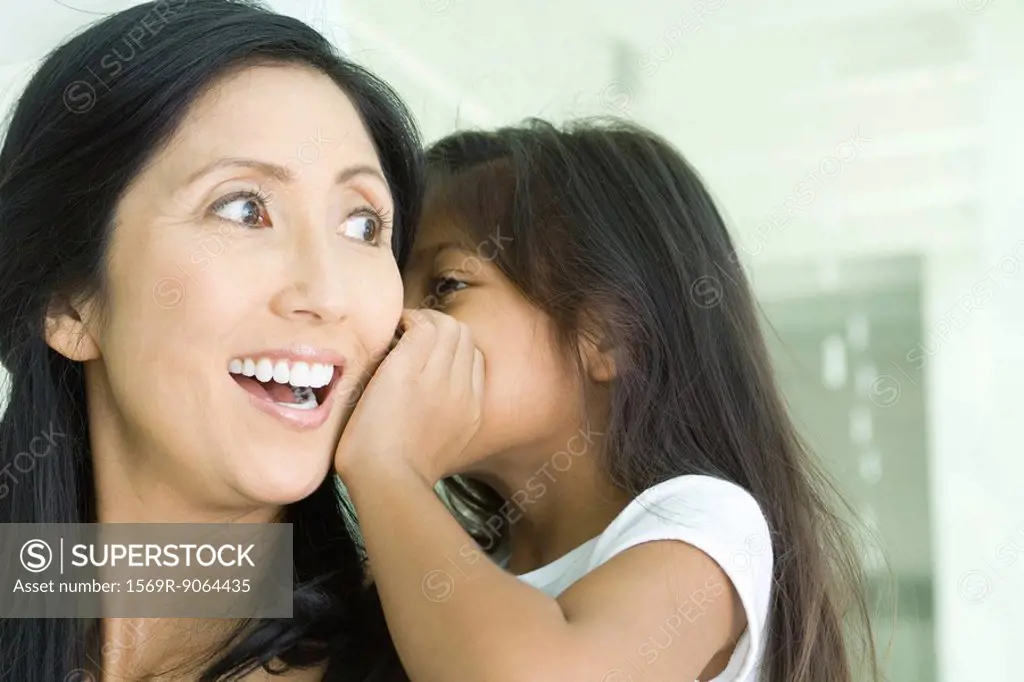 Girl whispering in mother´s ear, close-up