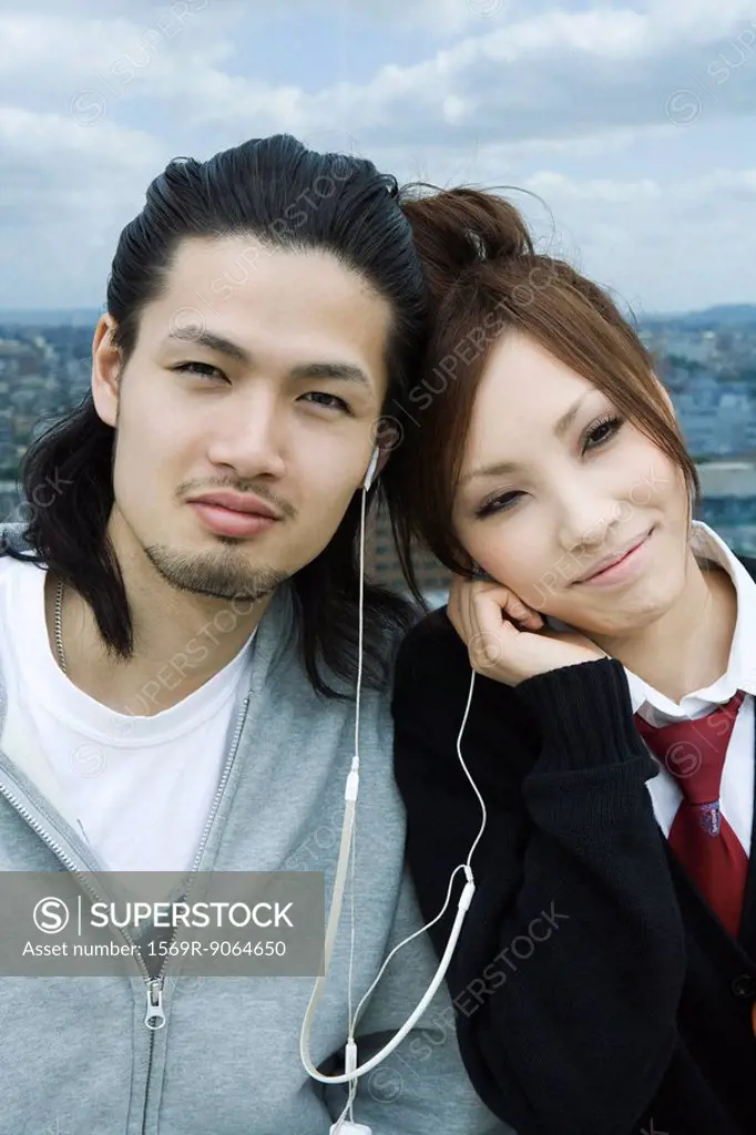 Young couple sharing earphones, smiling