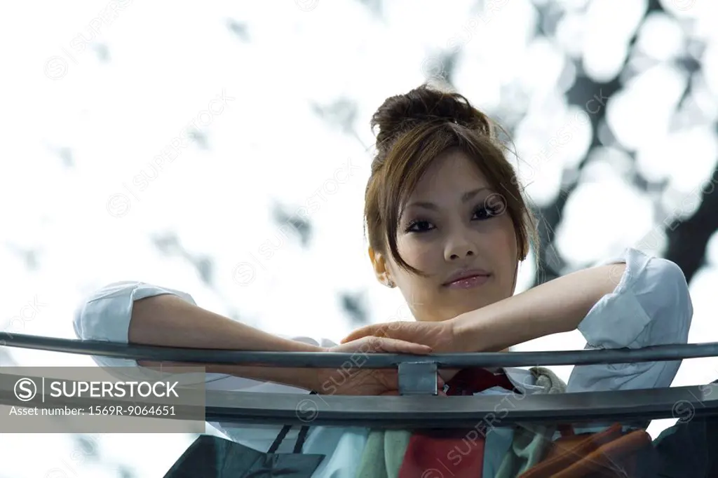 Female leaning against railing, smiling at camera, low angle view