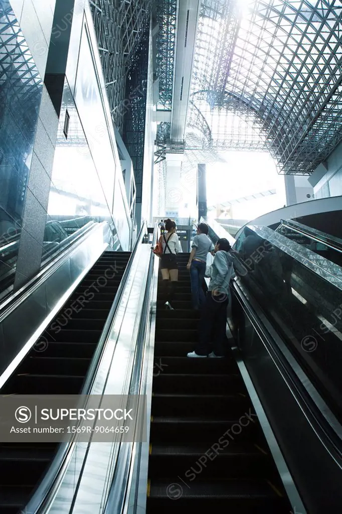 People going up escalator, rear view
