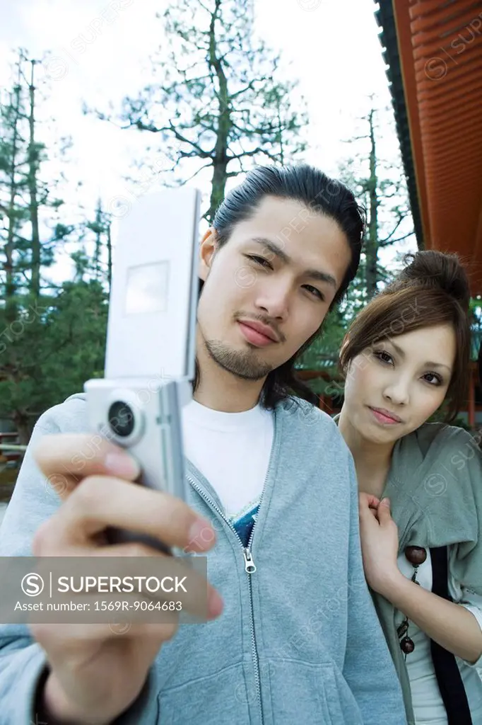 Young couple photographing selves with cell phone