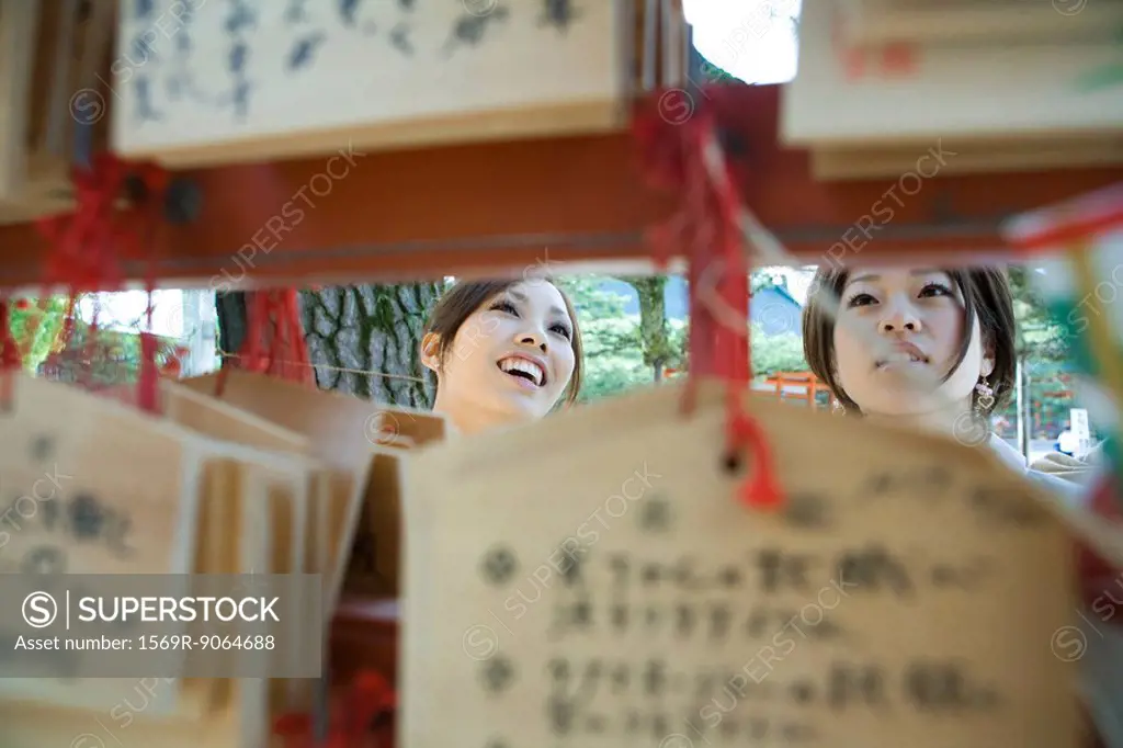Young females looking at traditional Japanese ema wishes in Shinto shrine