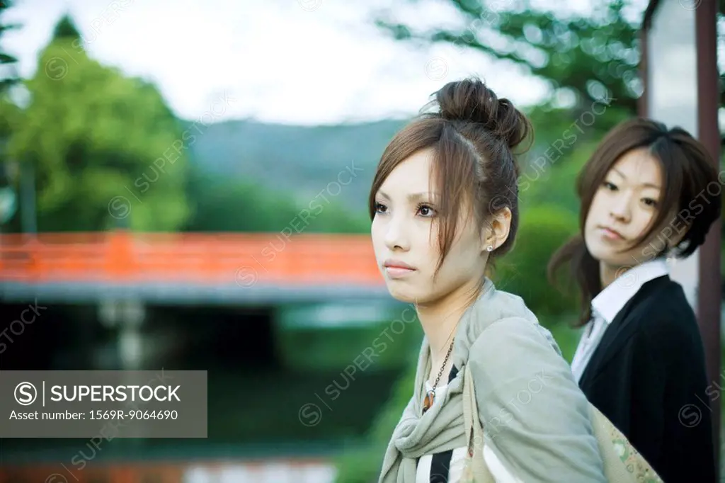 Young females outdoors, looking away, bridge in background