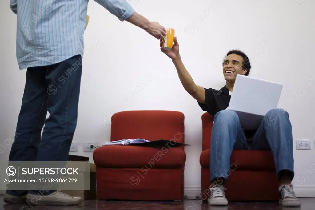 Man handing coffee cup to colleague